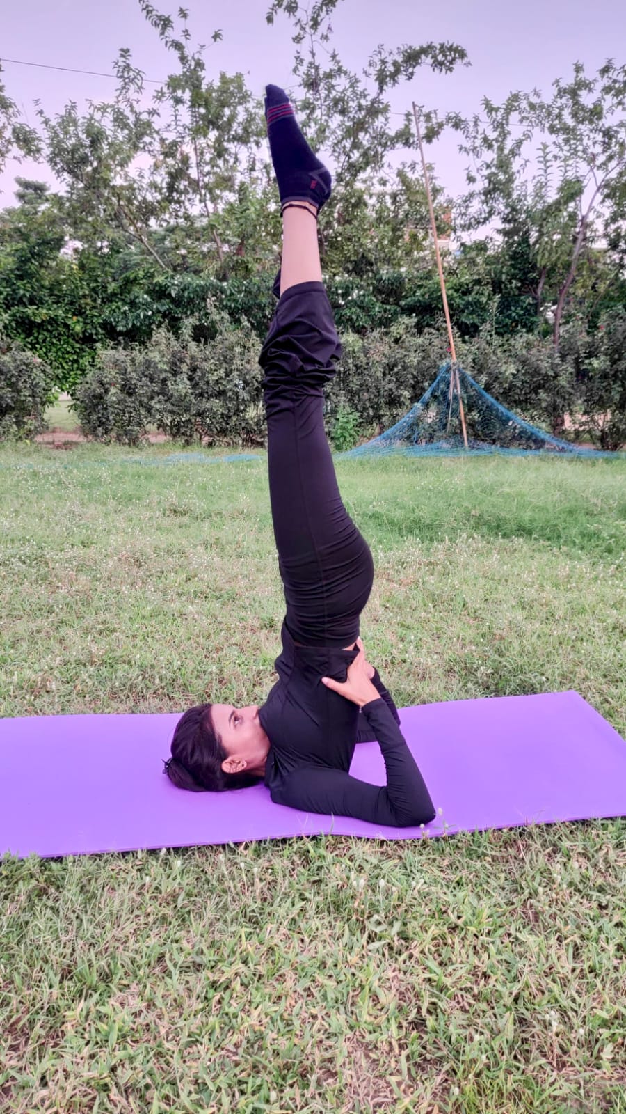 Priya in shoulder stand on the mat outdoors